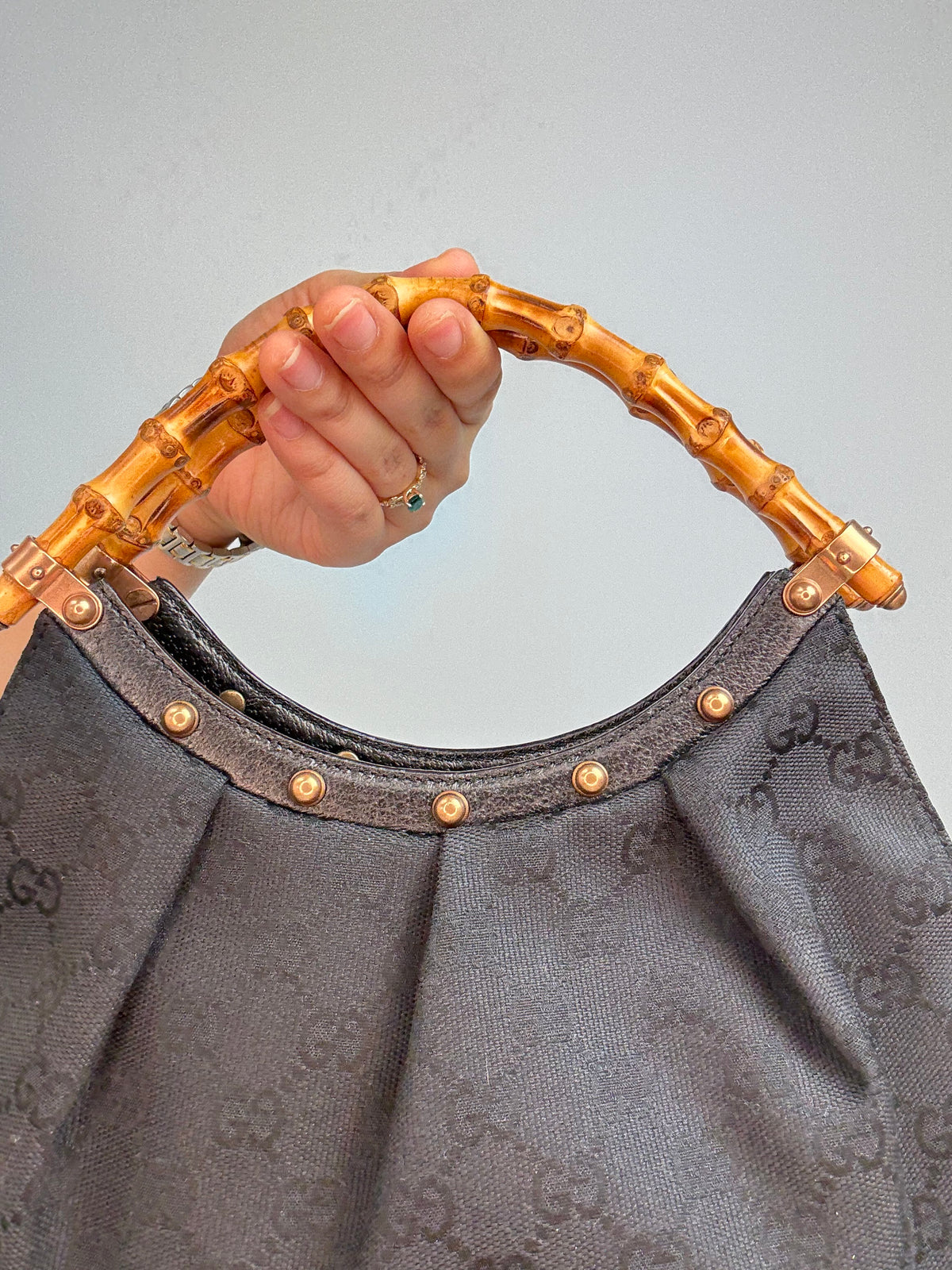 Gucci bag in black GG canvas with studded detailing and a bamboo handle.
Front of Bag Close-up