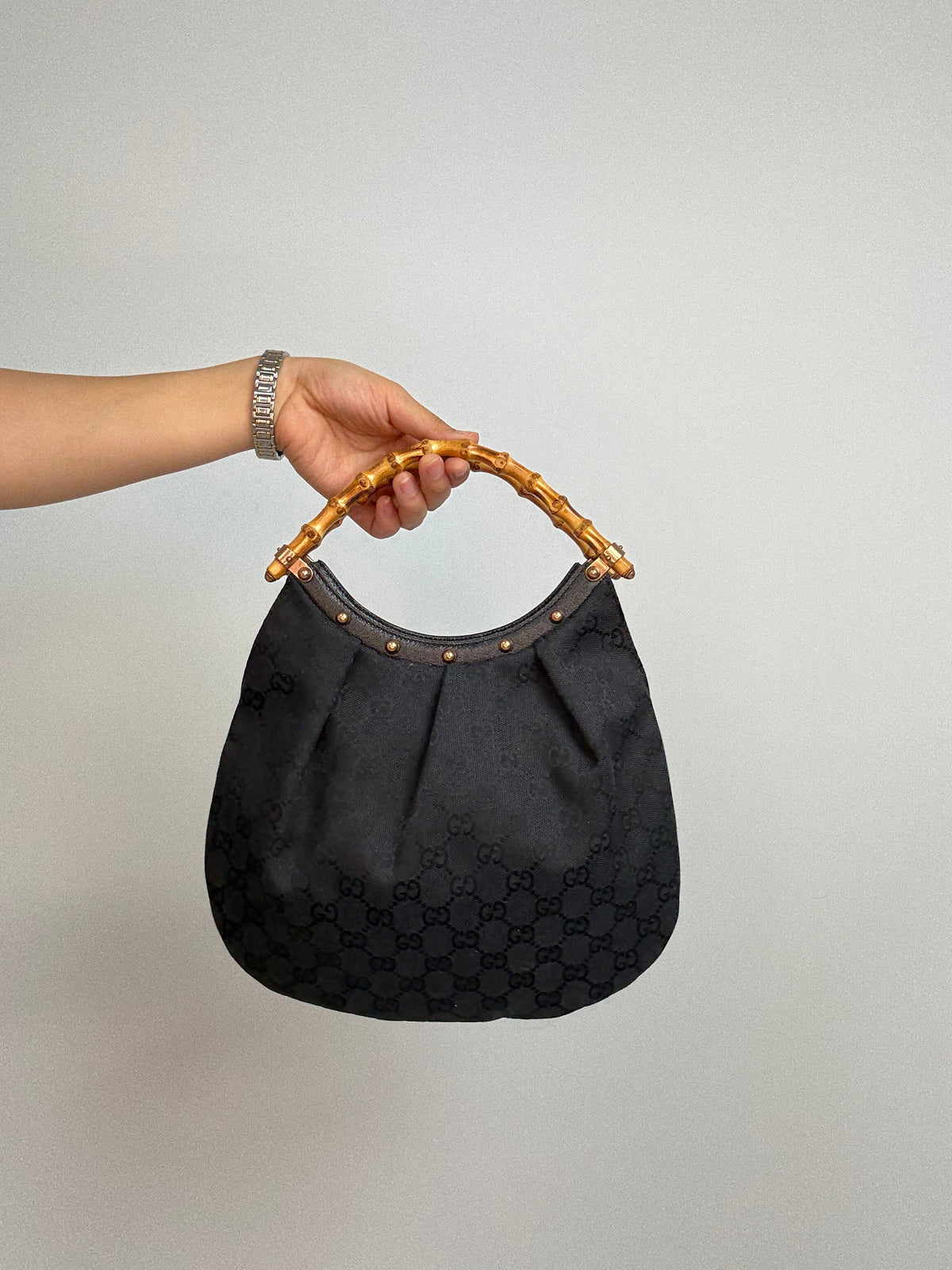 Gucci bag in black GG canvas with studded detailing and a bamboo handle. Front of Bag