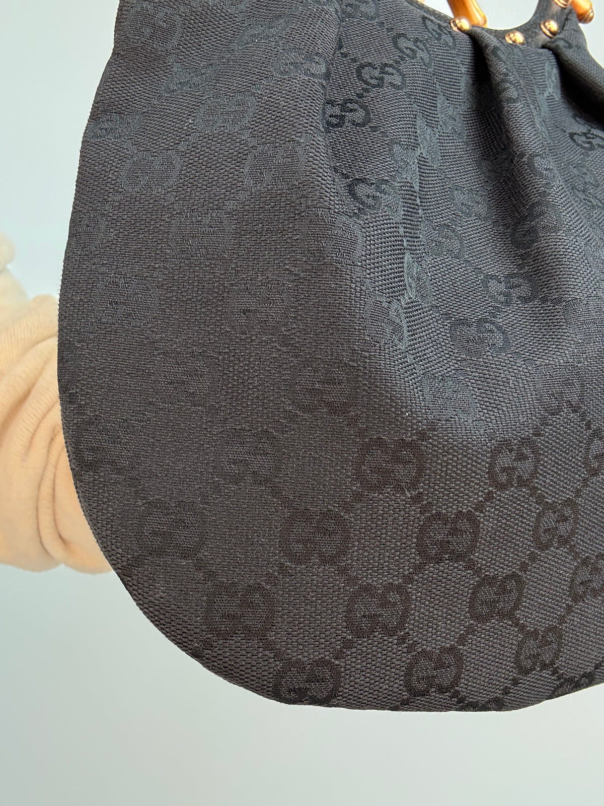 Gucci bag in black GG canvas with studded detailing and a bamboo handle. Left Corner