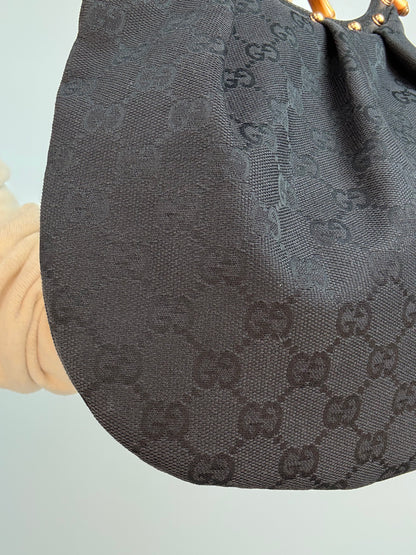 Gucci bag in black GG canvas with studded detailing and a bamboo handle. Left Corner