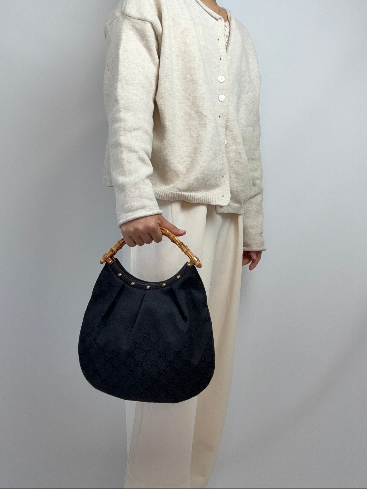 Gucci bag in black GG canvas with studded detailing and a bamboo handle. On Model Handheld