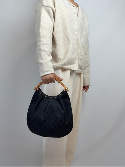 Gucci bag in black GG canvas with studded detailing and a bamboo handle. On Model Handheld